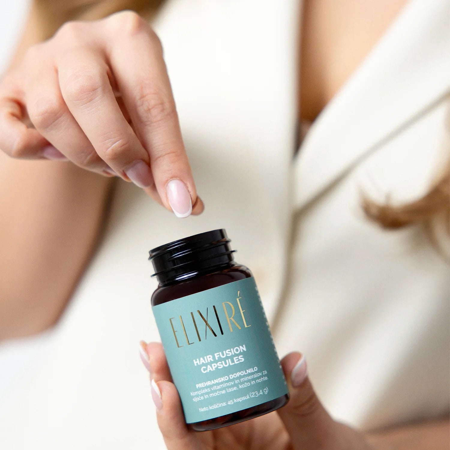 Roka odpira stekleničko Elixiré Hair Fusion Capsules — premium kakovost iz Slovenije
